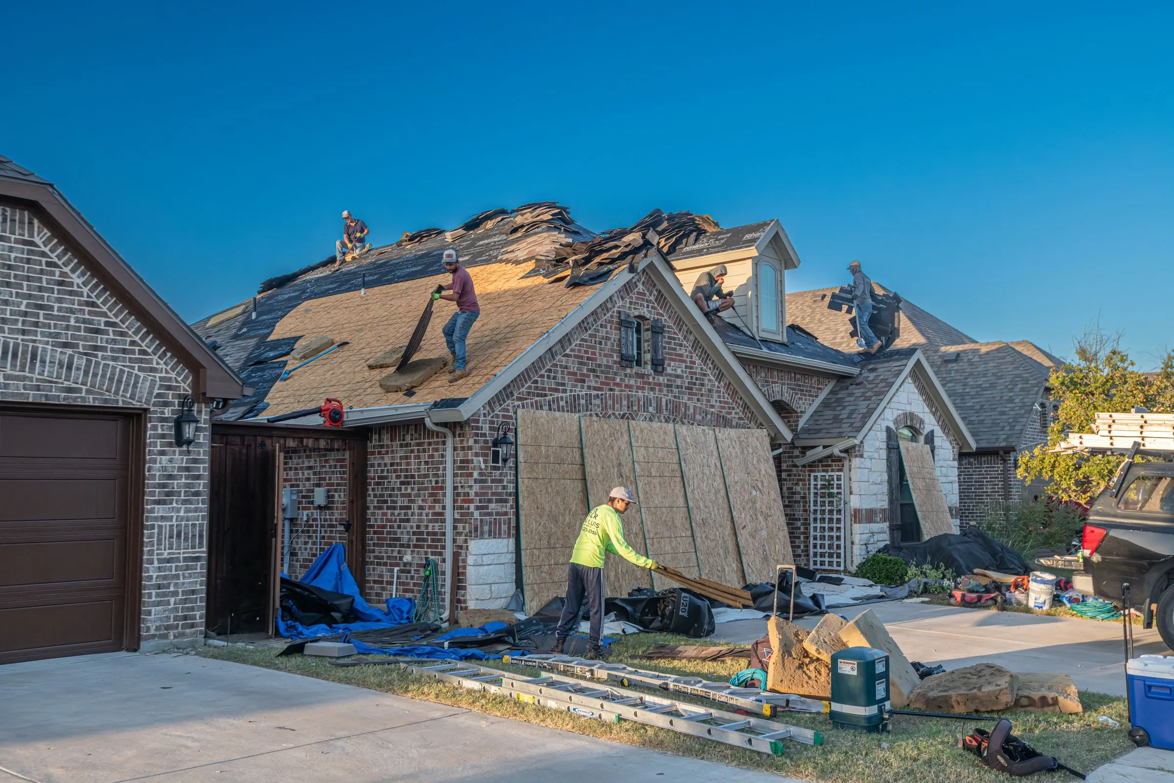 Roofing crew tearing off an old roof on a brick home